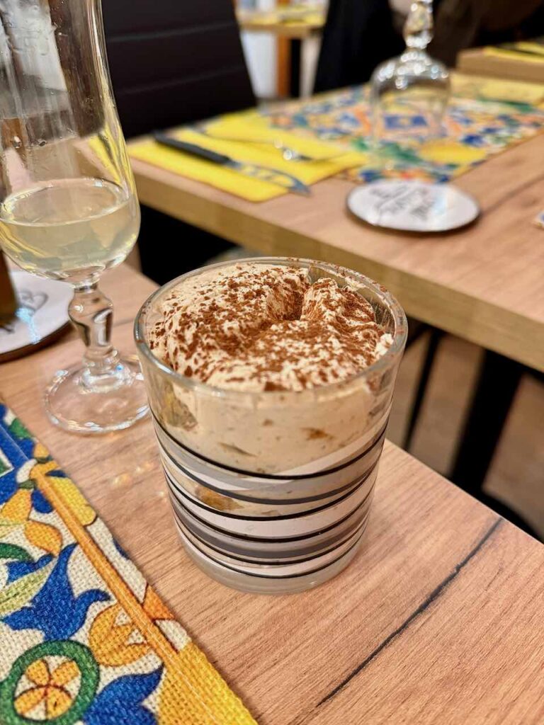 Tiramisu dans un verre à rayures noires sur une table en bois