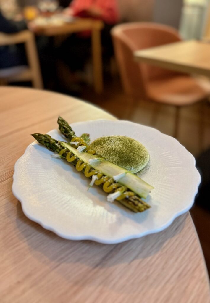 Asperges vertes cuite et cru dans une assiette blanche plate à liserés