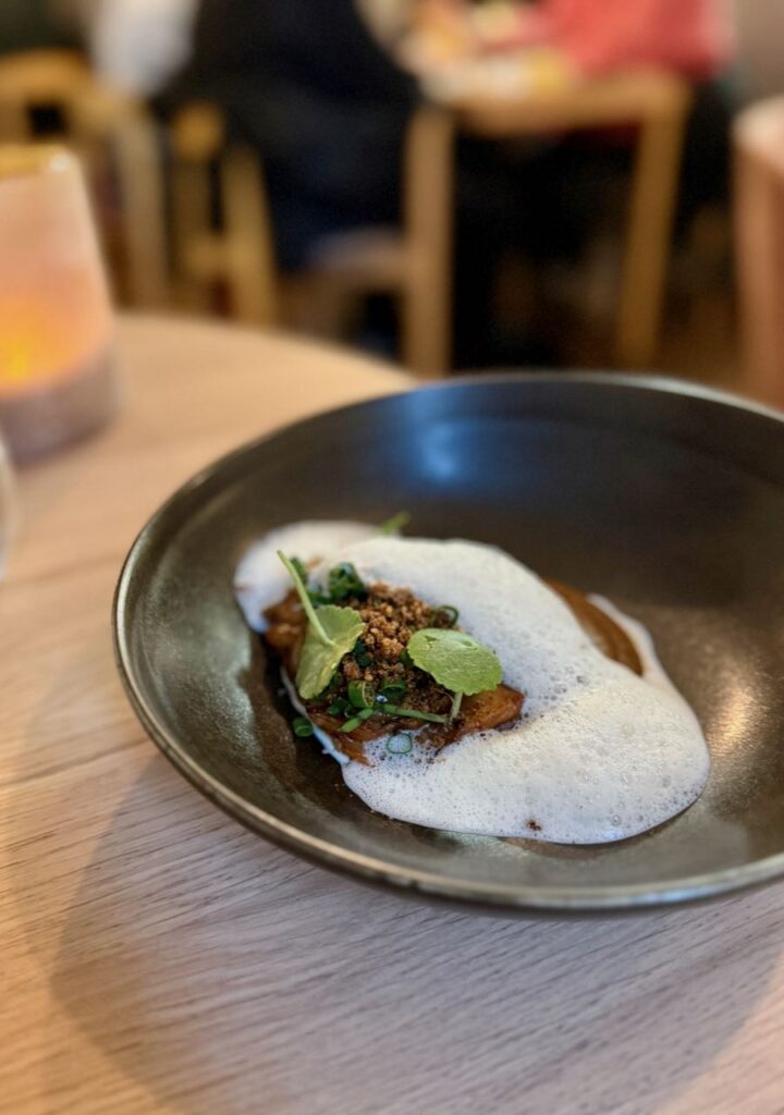 Crumble d'oignon et espuma dans une assiette en grès gris foncé