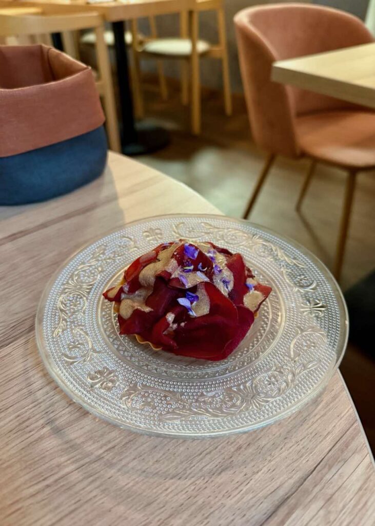 Tartelette à la betterave surmontée de pétale dans une assiette en verre vintage