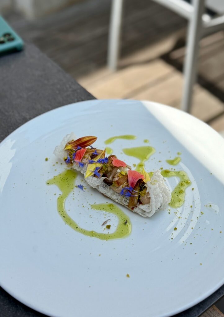 Ail des ours soufflé et pétales de fleurs dans une grande assiette blanche