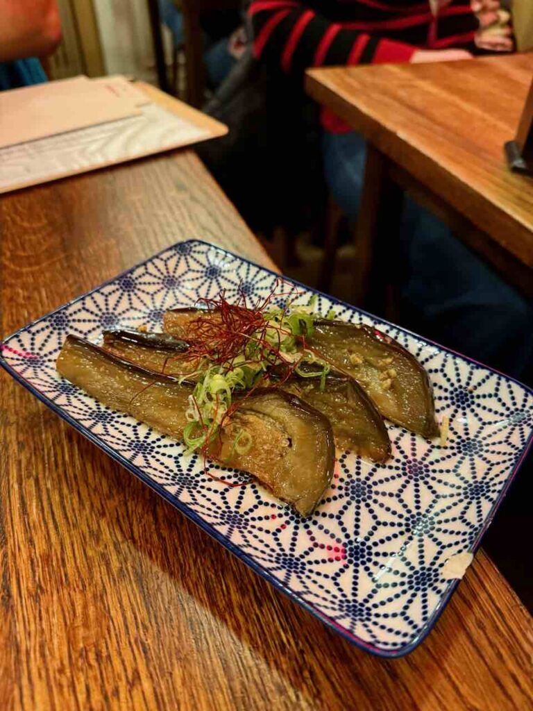 Aubergines marinées en tranches dans une assiette rectangulaire graphique