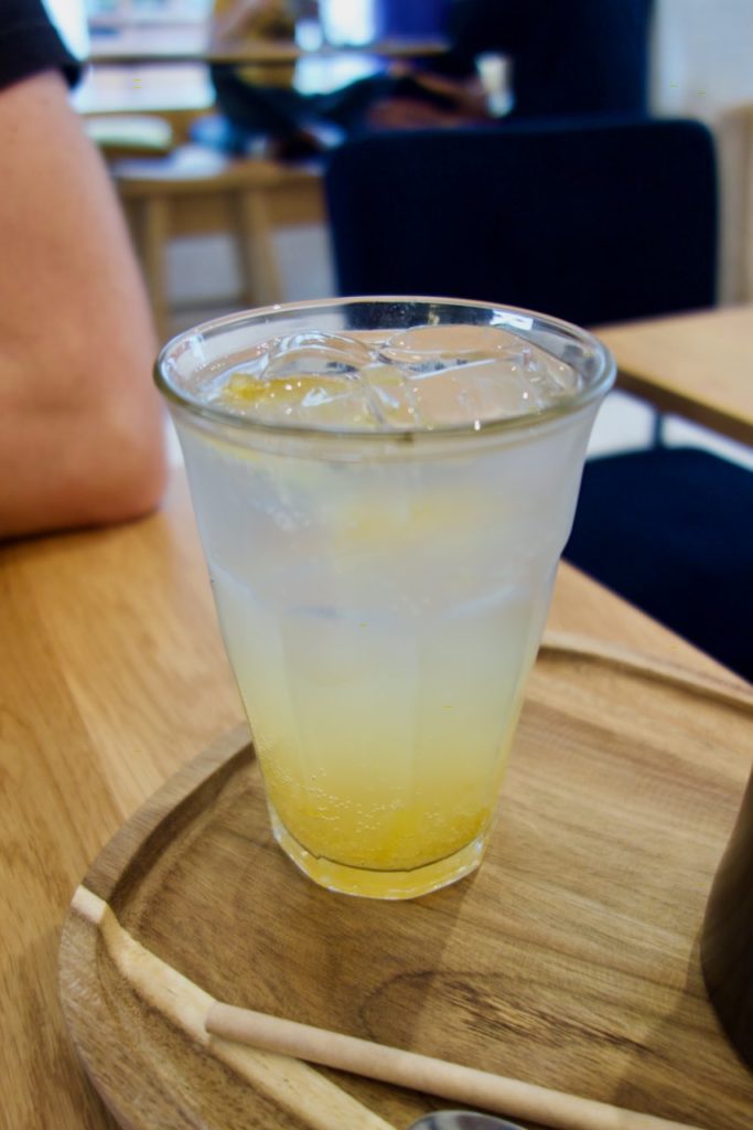limonade aux zestes de yuja dans un verre sur un plateau en bois