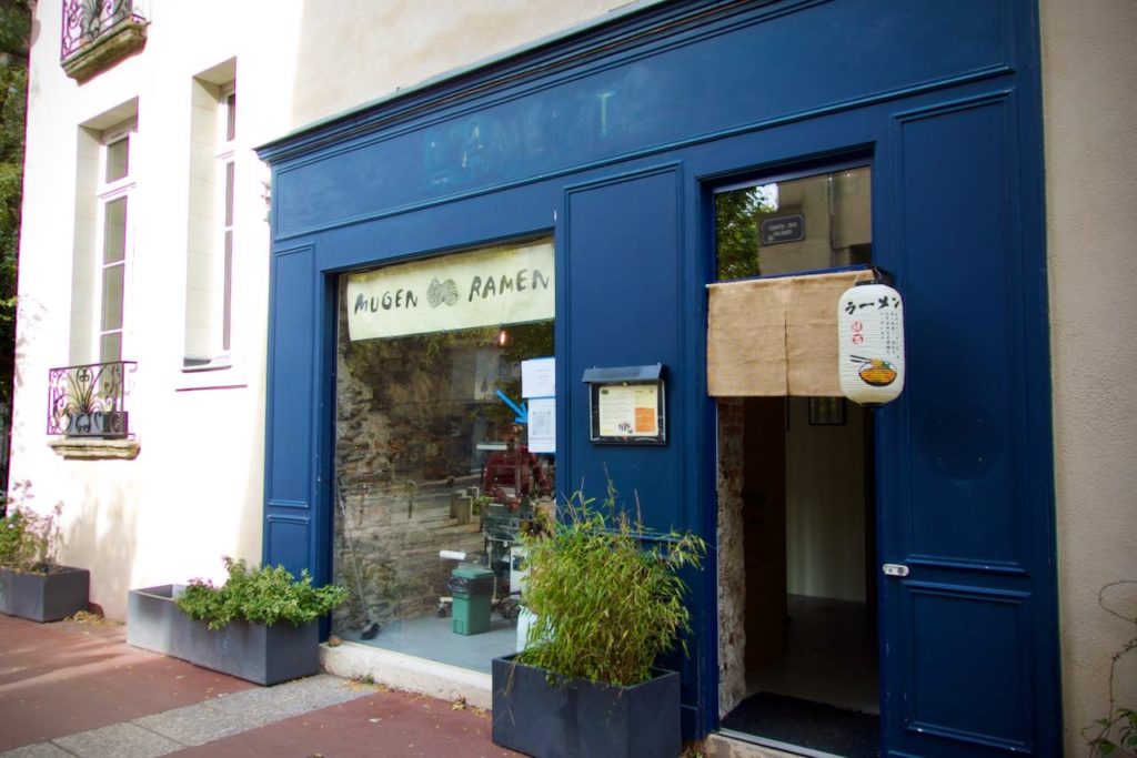 Devanture bleue du restaurant mugen ramen. Le nom du restaurant est imprimé sur un noren