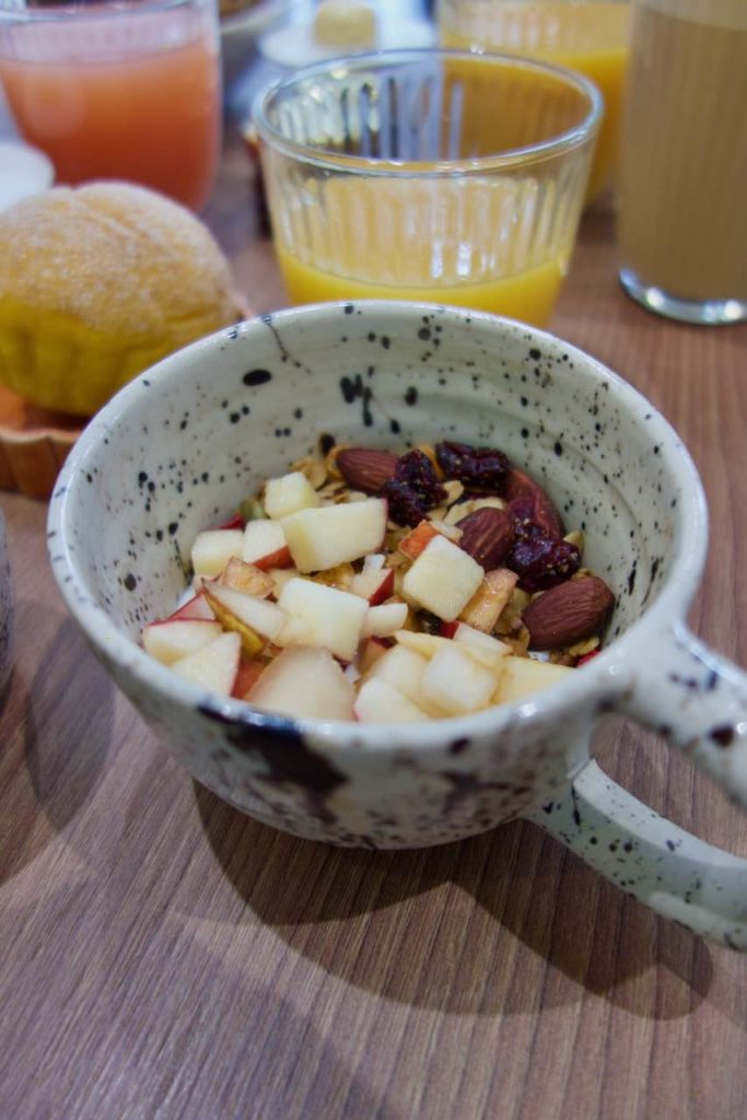 granola bowl aux fruits, fruits secs et fromage blanc dans une tasse en grès blanche mouchetée