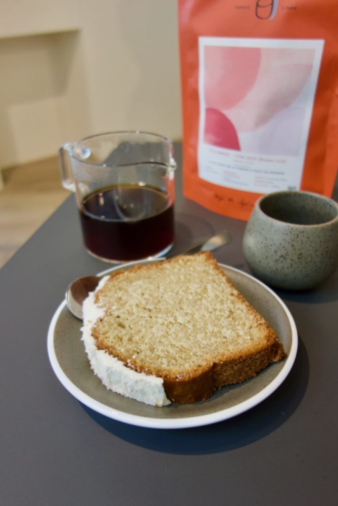Cake coco/vanille dans une assiette grise, tasse de café et sachet en arrière plan