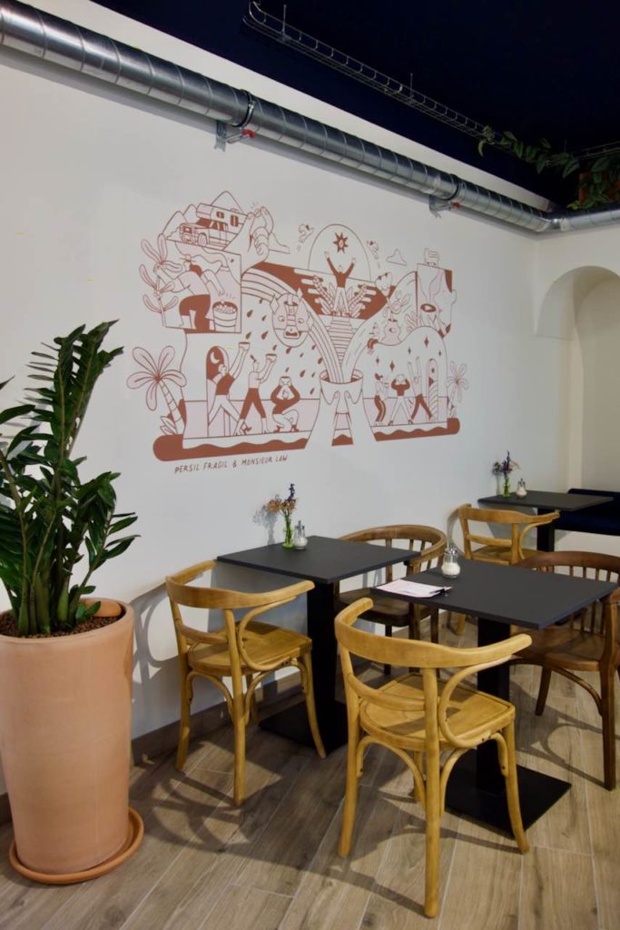 Plusieurs tables et chaises dans une salle dotée d'une fresque murale