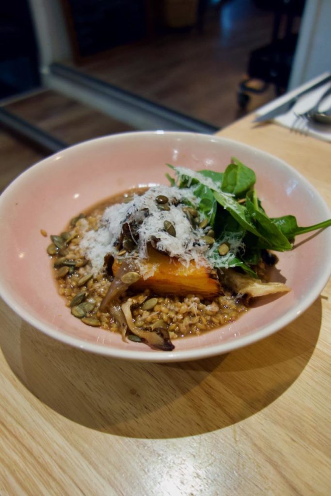 Assiette creuse rose contenant un risotto de petit épeautre sur une table en bois