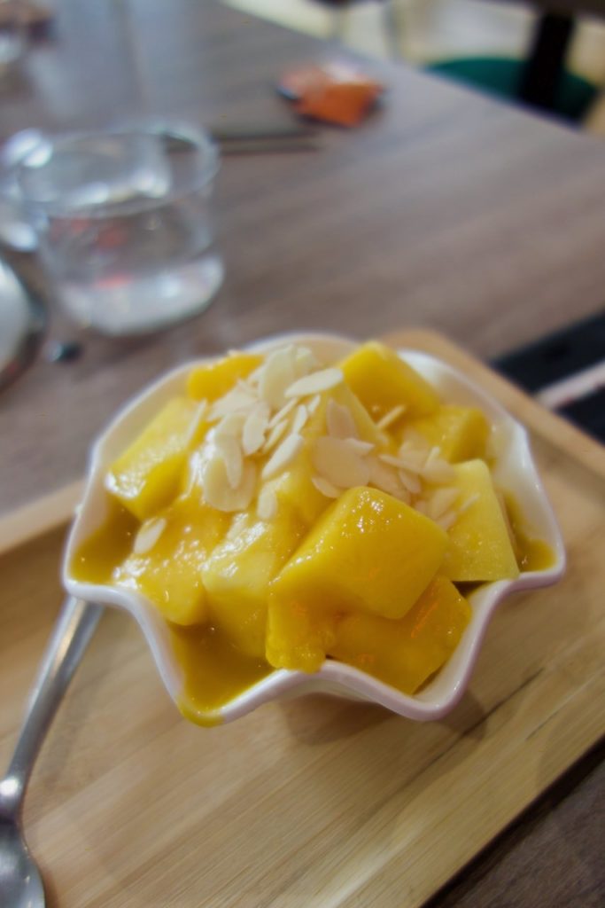 Bingsu à la mangue dans un bol blanc et sur un petit plateau en bois