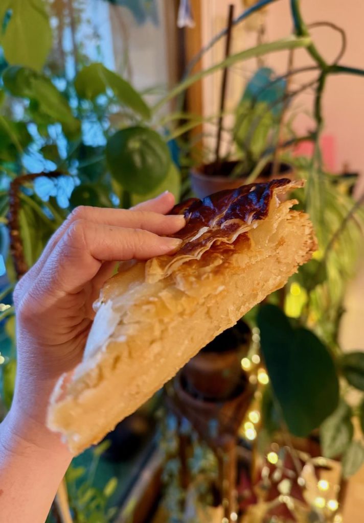Part de galette frangipane avec des plantes en fond