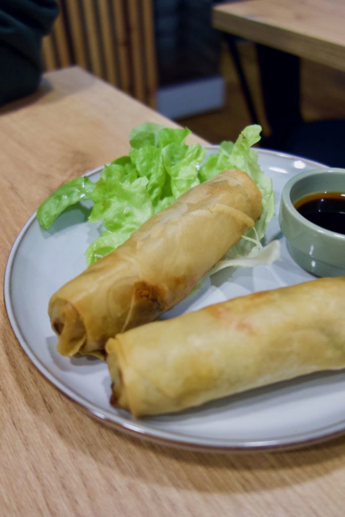 Deux nems dans une assiette blanche avec une feuille de salade