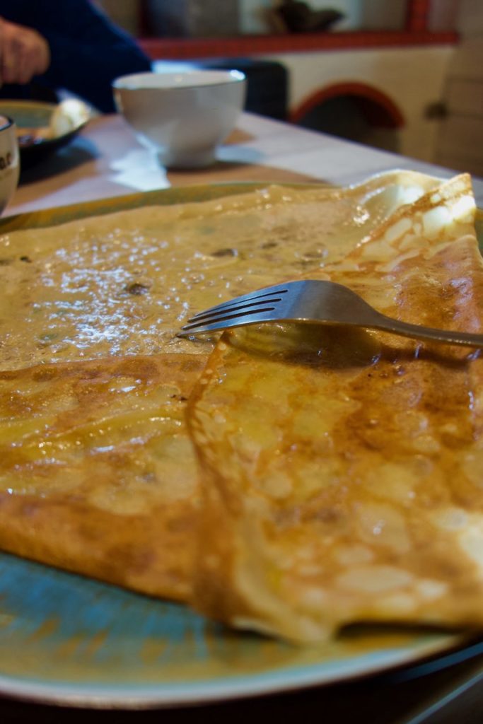 crêpe beurre et sucre dans une assiette bleue avec une fourchette dessus