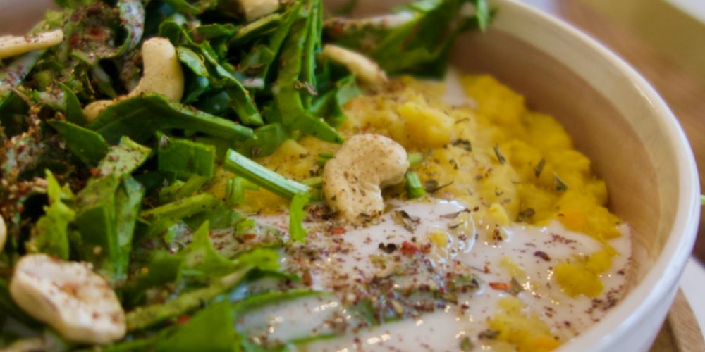 Dahl de lentilles corail, noix de cajou et épinards dans un bol blanc