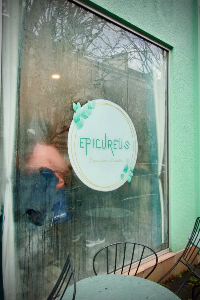Devanture verte du restaurant avec le logo Epicureus dans un cercle blanc