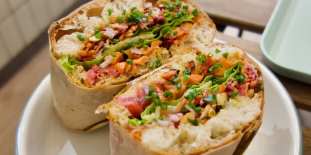 Focaccia garnie de légumes coupée droitement par le milieu dans une assiette blanche