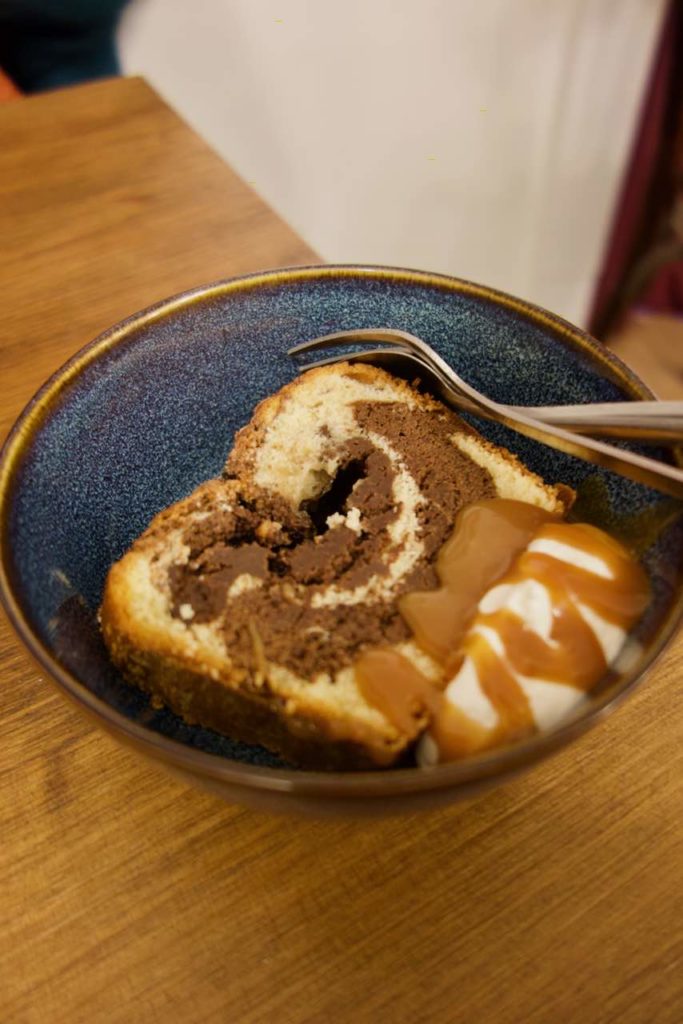 Gâteau marbré, chantilly et caramel dans un petit bol bleu en terre cuite sur une table en bois