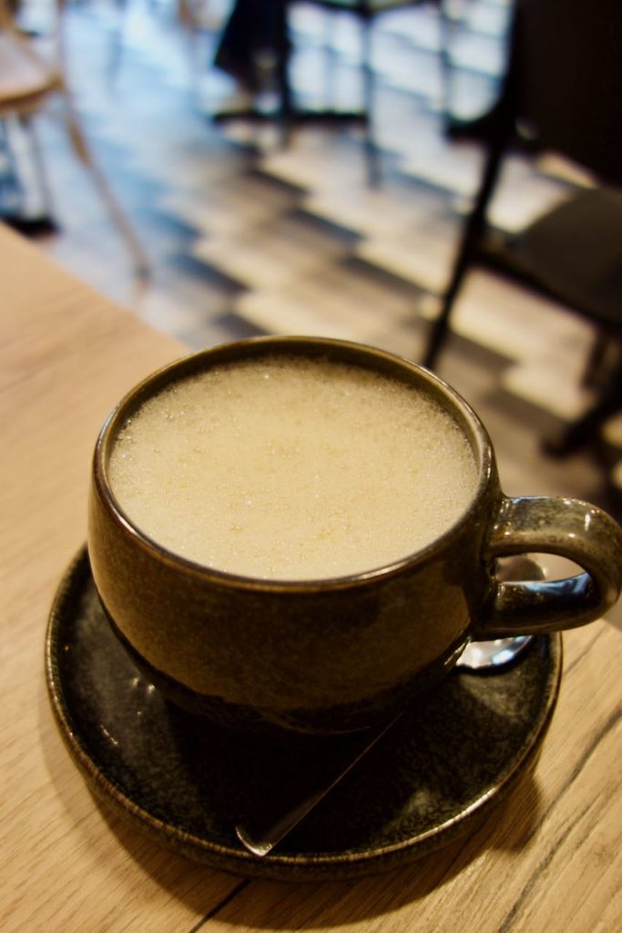 Golden latté dans une tasse noire sur une soucoupe noire
