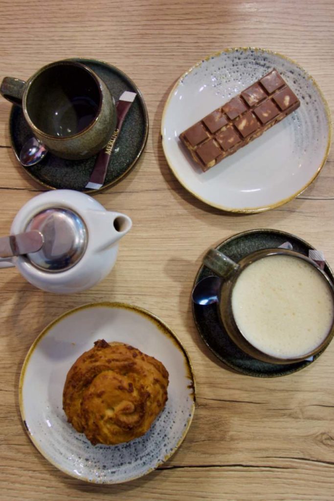 Vue de dessus d'une babka, une théière blanche, une tasse noire, un gâteau façon kinder country et une tasse noire de golden latté
