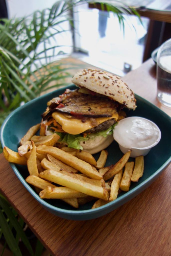 Burger, frites et pot de sauce tartare dans une assiette creuse en plastique bleue
