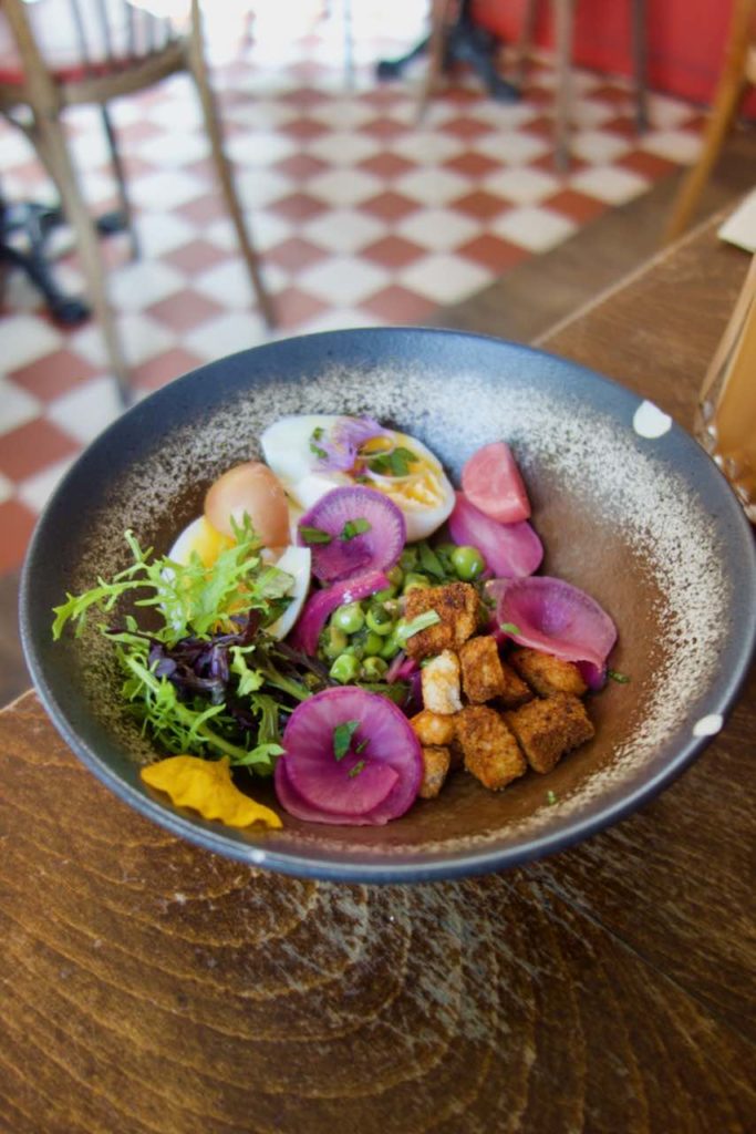 Assiette pleines de légumes colorées en grès gris sur une table en bois