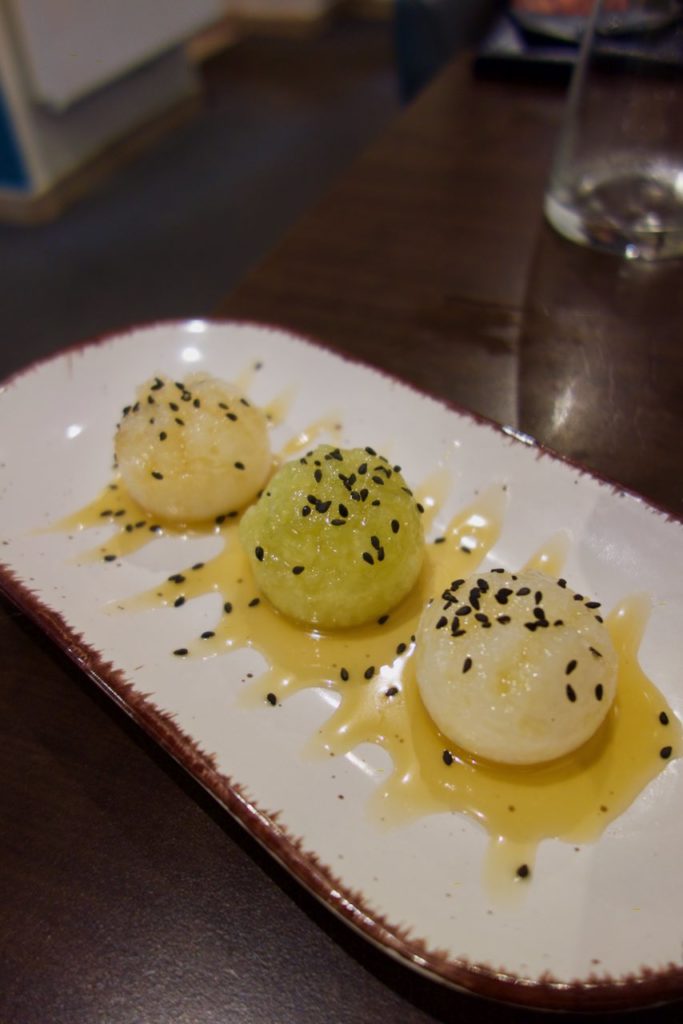 Trois boulettes de riz gluant, deux blanches et une verte sur un plateau blanc