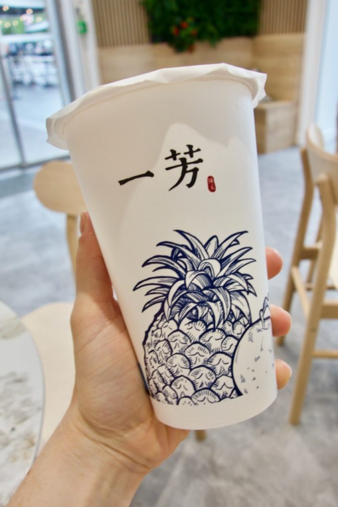 Bubble tea dans un contenant en carton avec le logo Yifang et une illustration d'un ananas