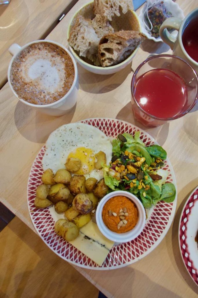 Brunch en vue du dessus avec une assiette salée, un verre de jus de pomme et framboise, un chocolat chaud et du pain