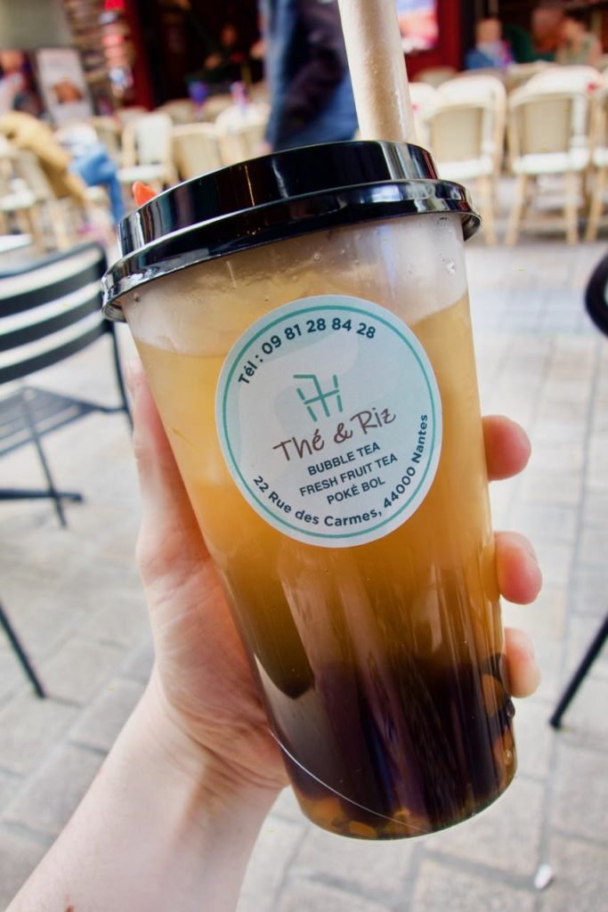 bubble tea à la pêche et perles de tapioca dans un contenant en plastique avec une opercule noire