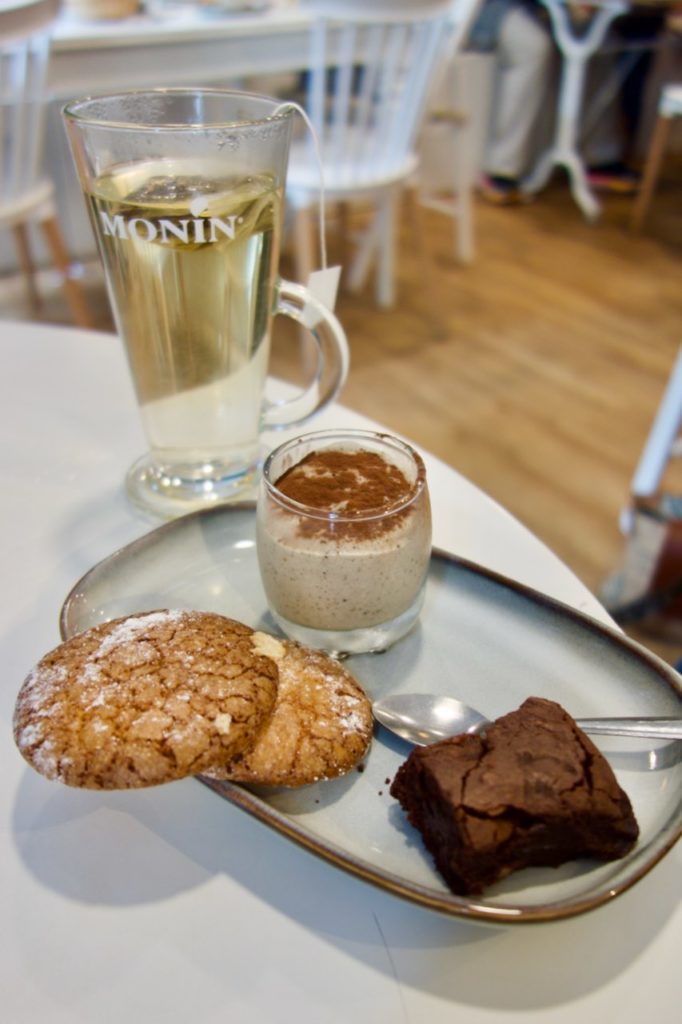 Thé dans un verre haut accompagné d'un trio de desserts sur un plat rectangulaire en grès