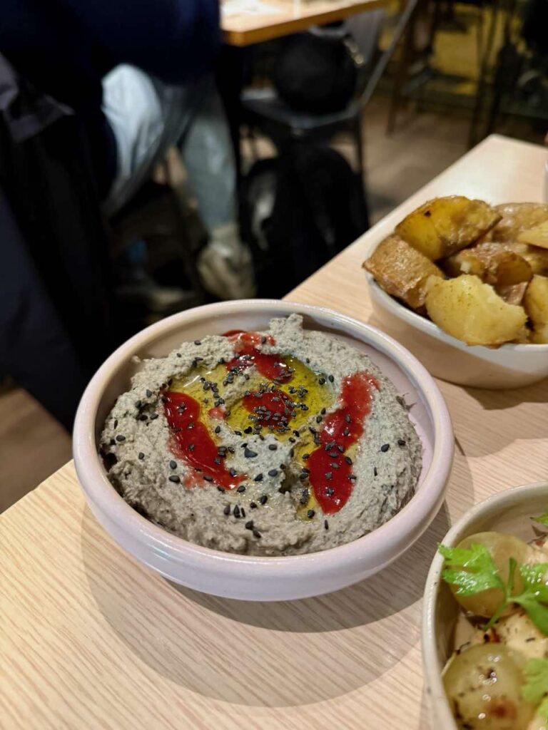 Houmous au sésame noir surmonté de coulis de fruits rouges dans un bol rond