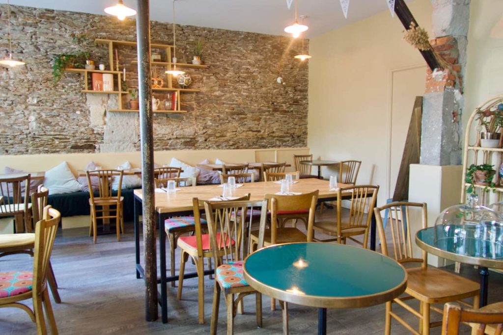 intérieur du café chez les crèmes avec des tables bistro bleues, des tables et des chaises en bois et un mur en bois