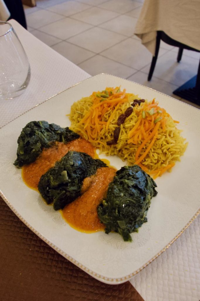 Epinard surmonté de sauce tomate et accompagné d'un riz épicé aux raisins secs dans une assiette blanche