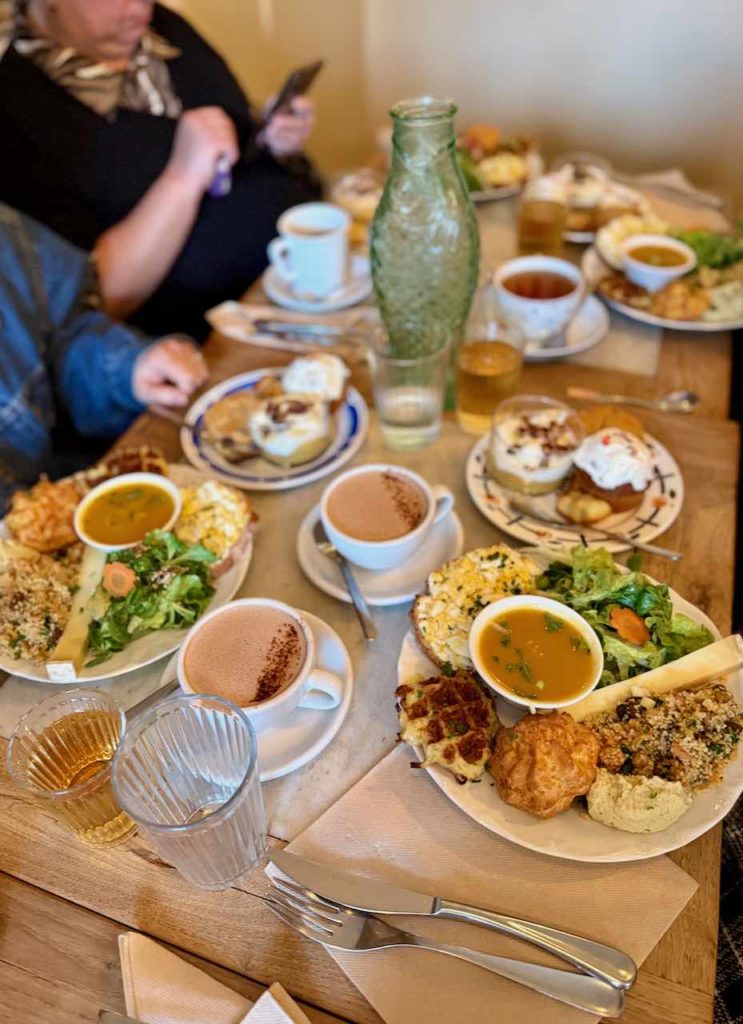 Vue de la tablée lors du brunch avec plein d'assiettes et de tasses remplies sur la table