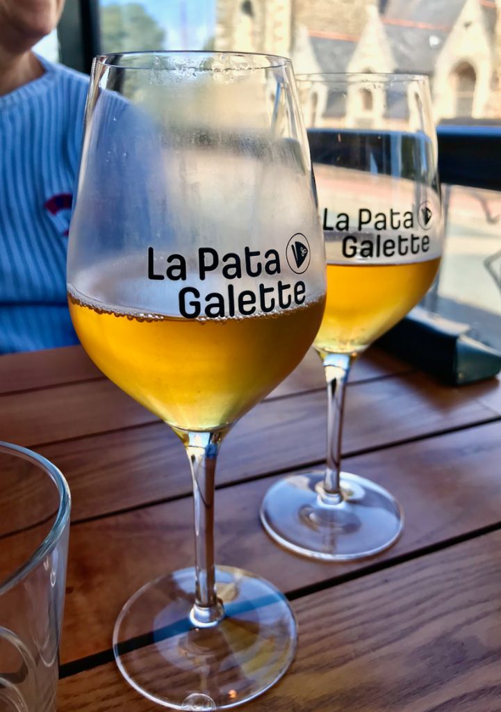 Deux verres transparents contenant du cidre sur une table en bois