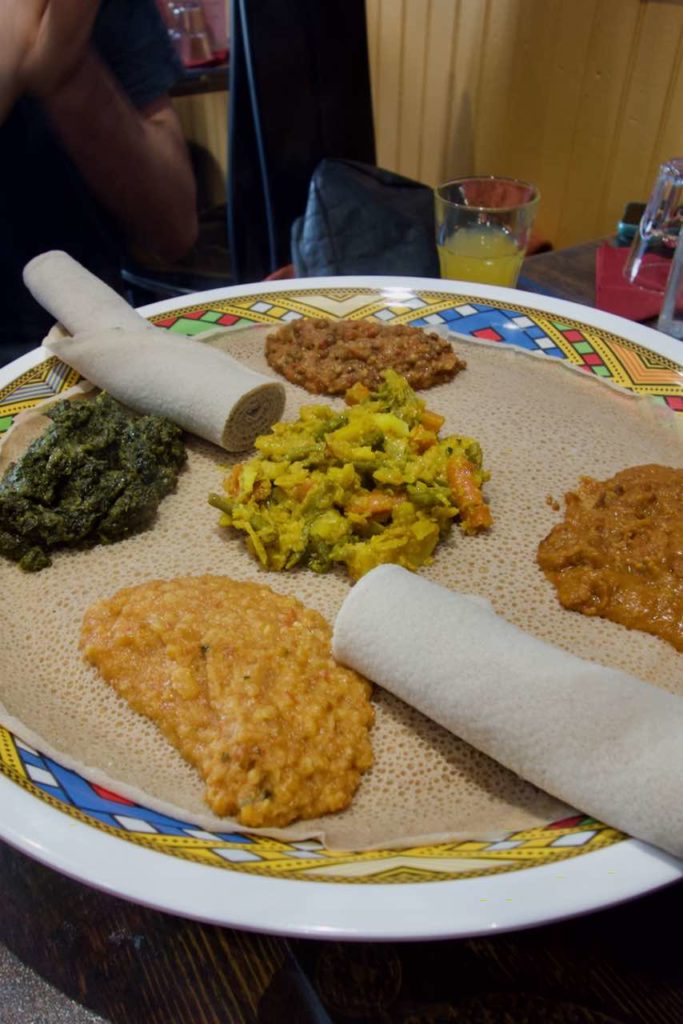 Injera sur laquelle sont posés cinq wats et deux rouleaux d'injera