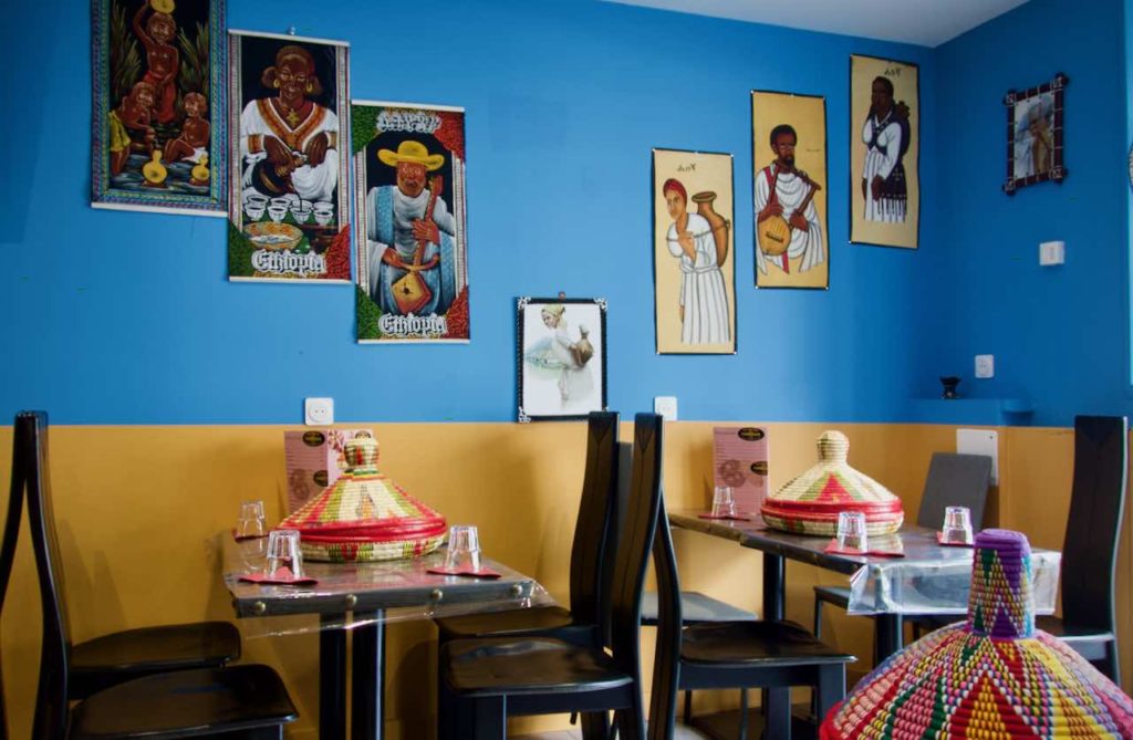 Intérieur du restaurant avec des tables et chaises noires, des portraits au mur