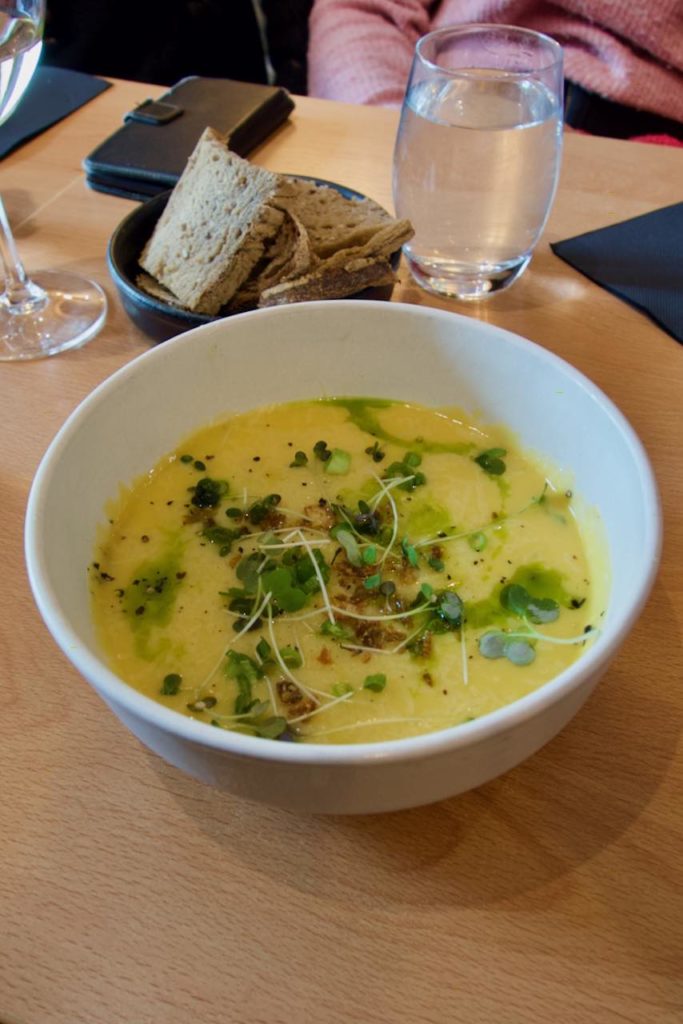 Velouté de courge et micro pousse dans un bol blanc