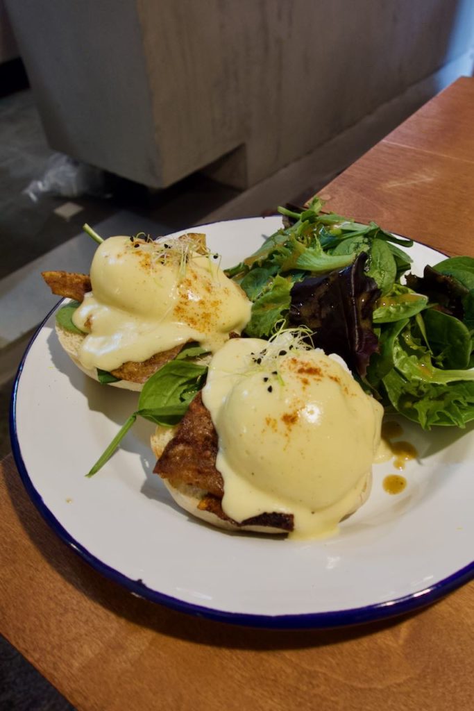 Deux oeufs bénéficte avec une salade dans une assiette blanche