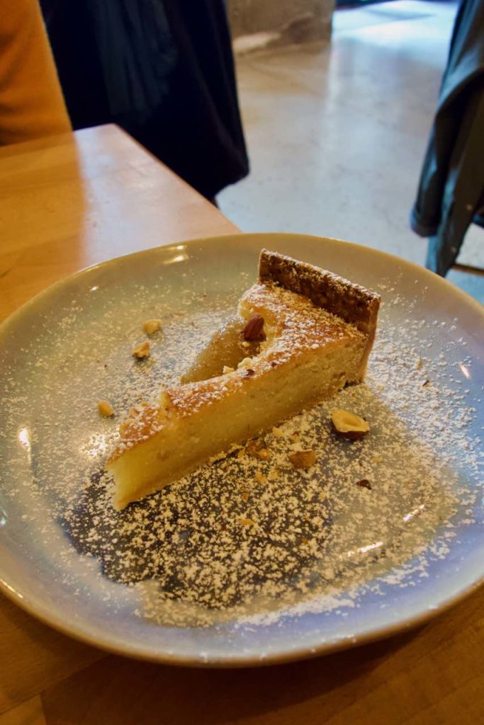 Part de tarte amandine saupoudré de sucre glace et de noisettes concassées