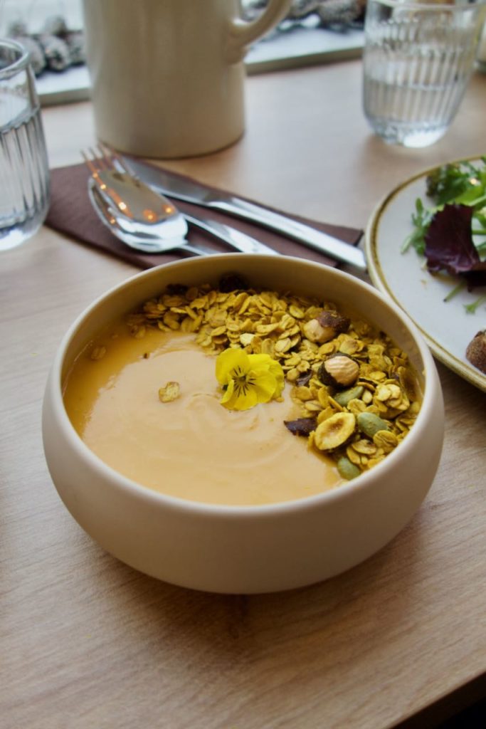Soupe de butternut et granola dans un bol rond en terre