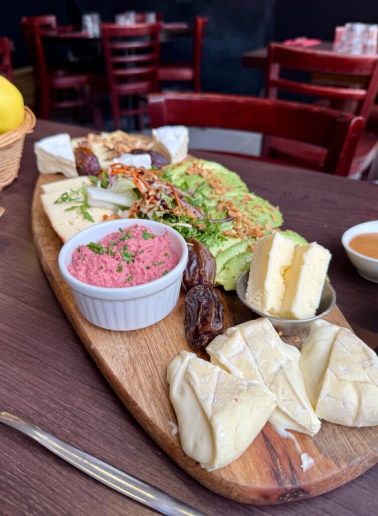 Planche allongée de fromage, avocat, houmous, beurre et figues