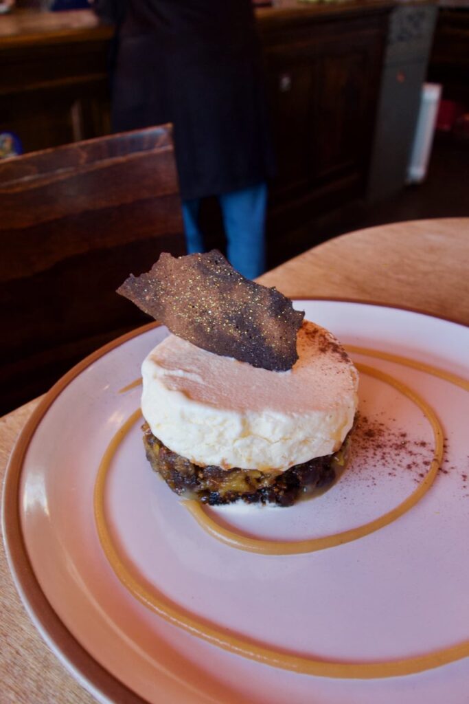 Dessert palestinien surmonté d'une tuile pailletée dans une assiette blanche à liseré ocre