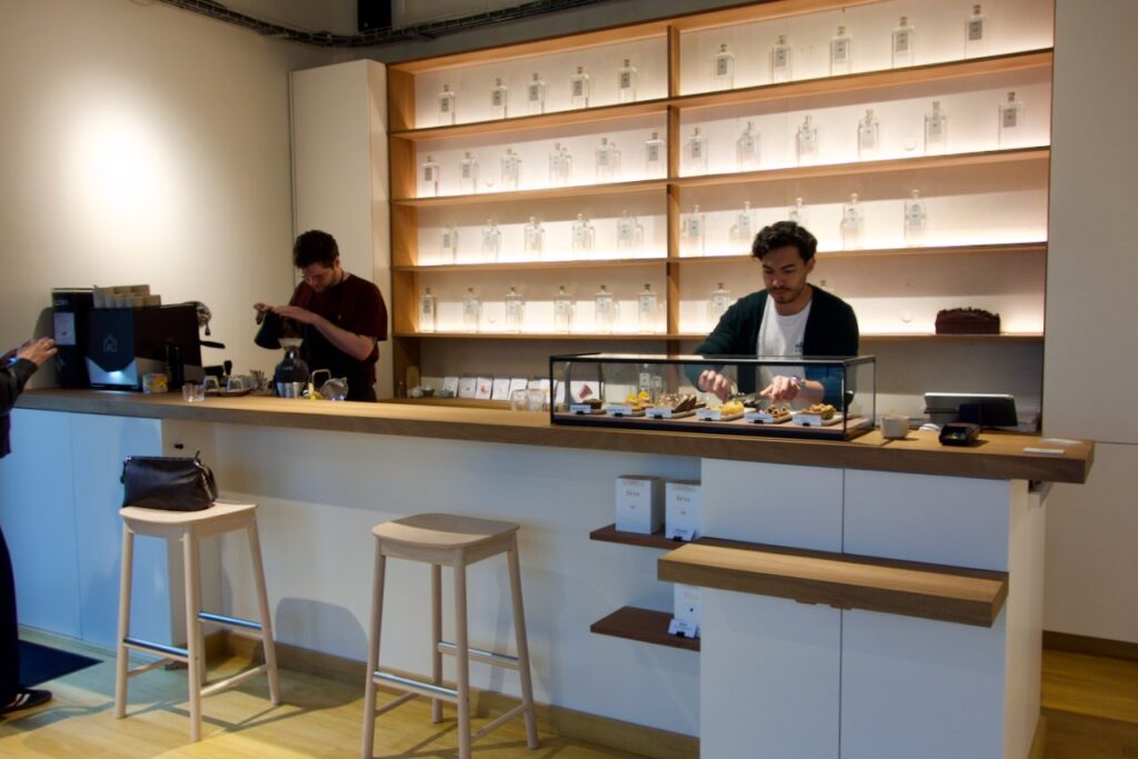 Bar du café avec une vitrine de pâtisseries et des bouteilles de gin sur des étagères en arrière plan