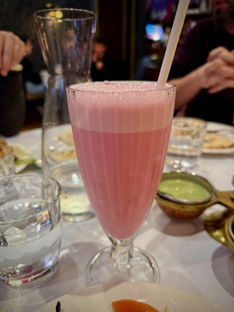 Lassi à la rose dans un grand verre à pied avec une paille