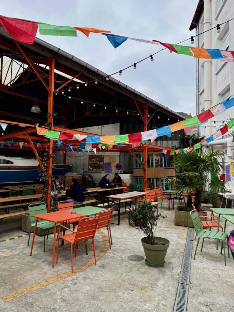Cour intérieure du Lieu-Dit avec tables et chaises en métal coloré