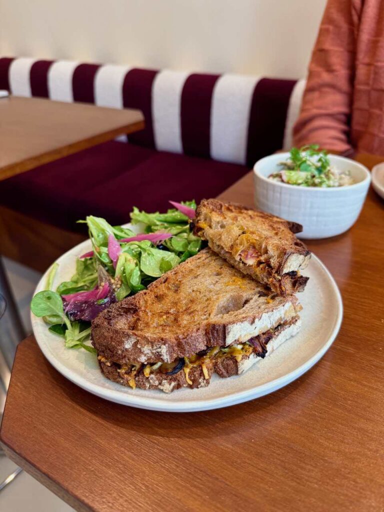 Grilled cheese et salade dans une assiette en grès sur une table en bois type acajou