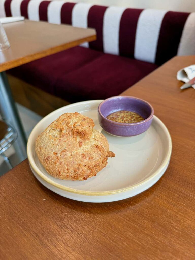 Pain au fromage et sauce moutarde dans une assiette ronde en grès blanc cassé