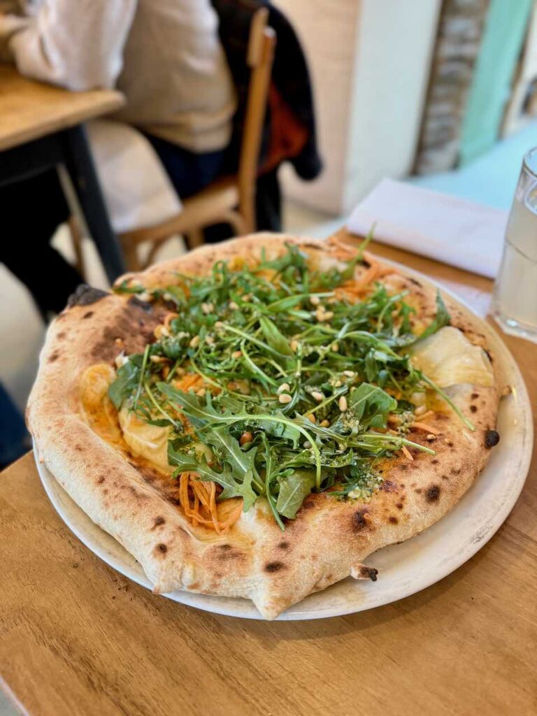 Pizza avec un généreux topping roquette dans une grande assiette blanche