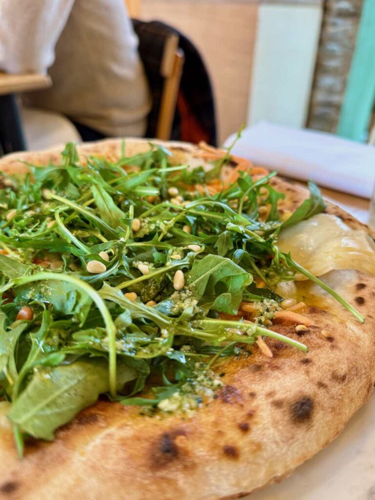 Gros plan sur la roquette, les pignons de pin, le pesto et la croûte épaisse