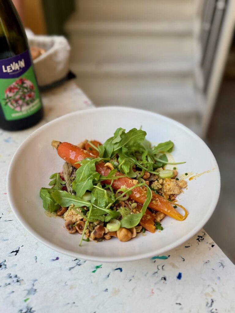 Carotte, mesclun et crumble dans une assiette creuse blanche
